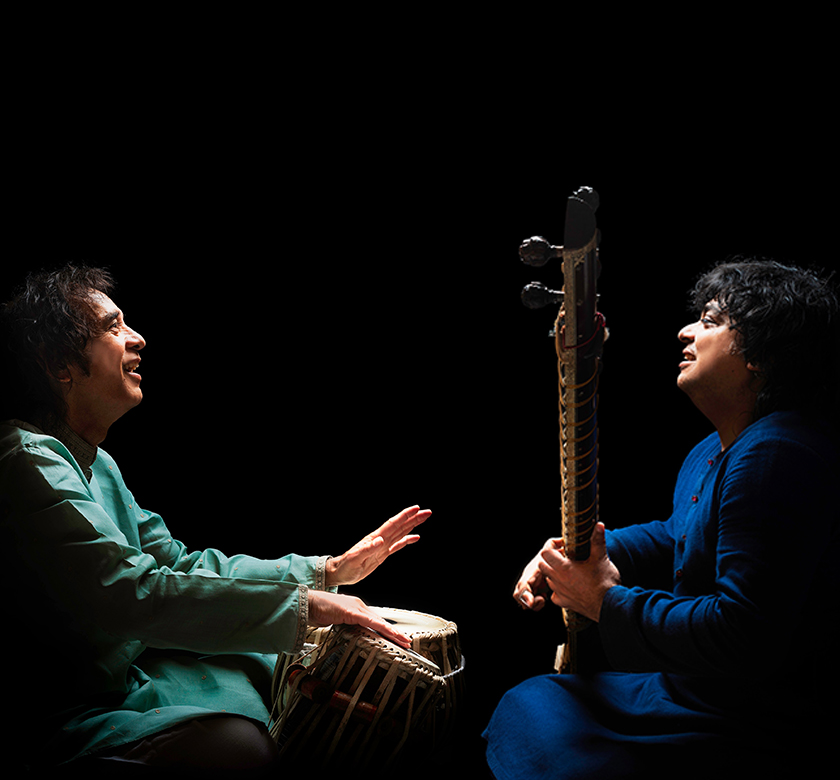 Image of two musicians playing together in front of a black background.